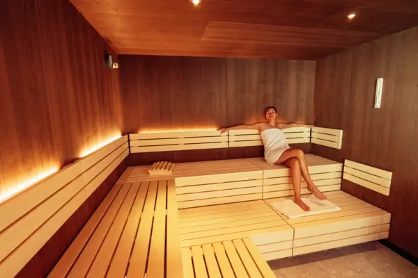 Eine Frau in einem Handtuch sitzt auf einer Bank in einer Sauna.