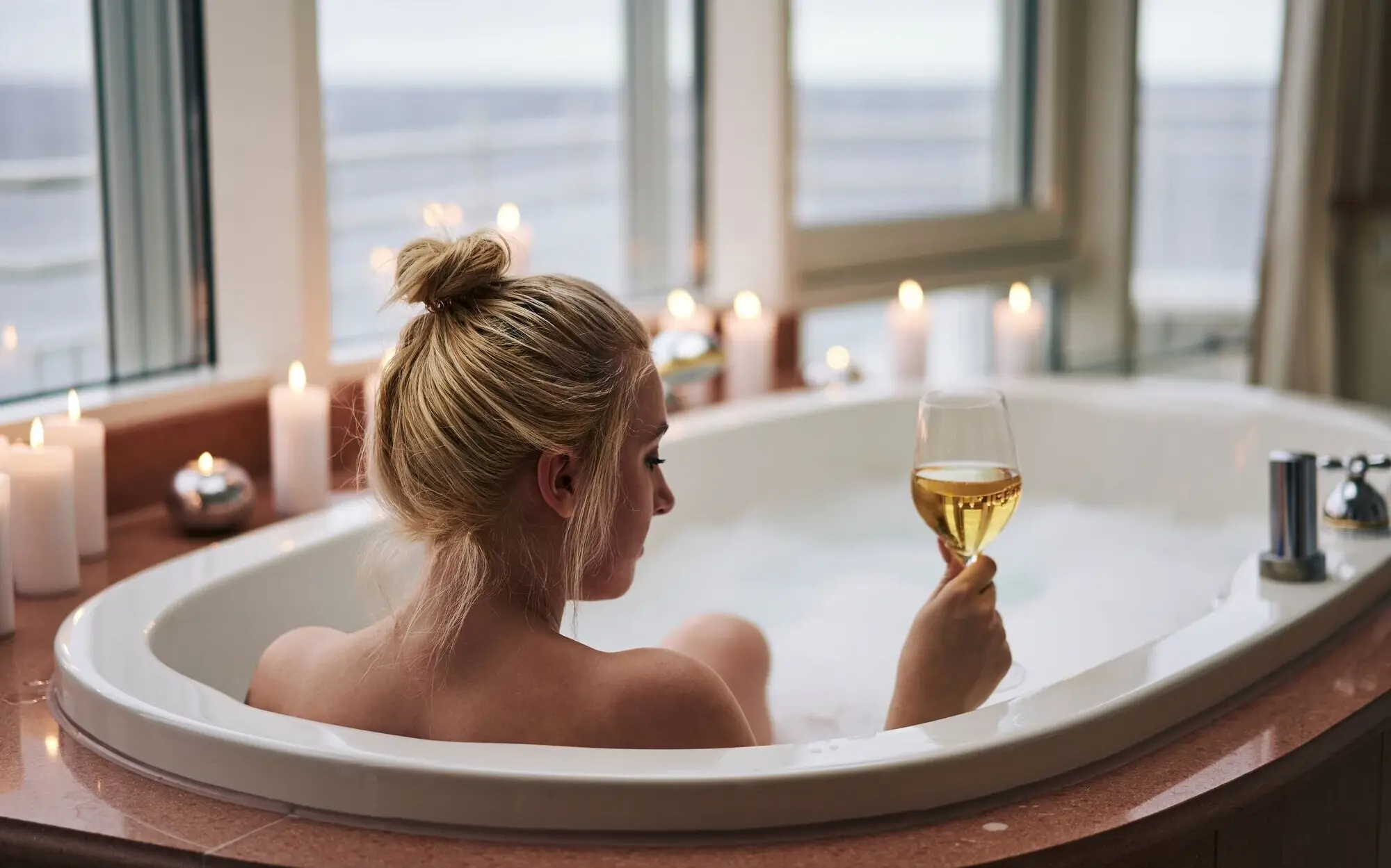 Penthouse-Suite aja Bansin Eine Frau in einer Badewanne hält ein Glas Wein.