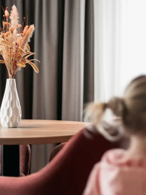 Ein Mädchen sitzt an einem Tisch mit einer Blumenvase.