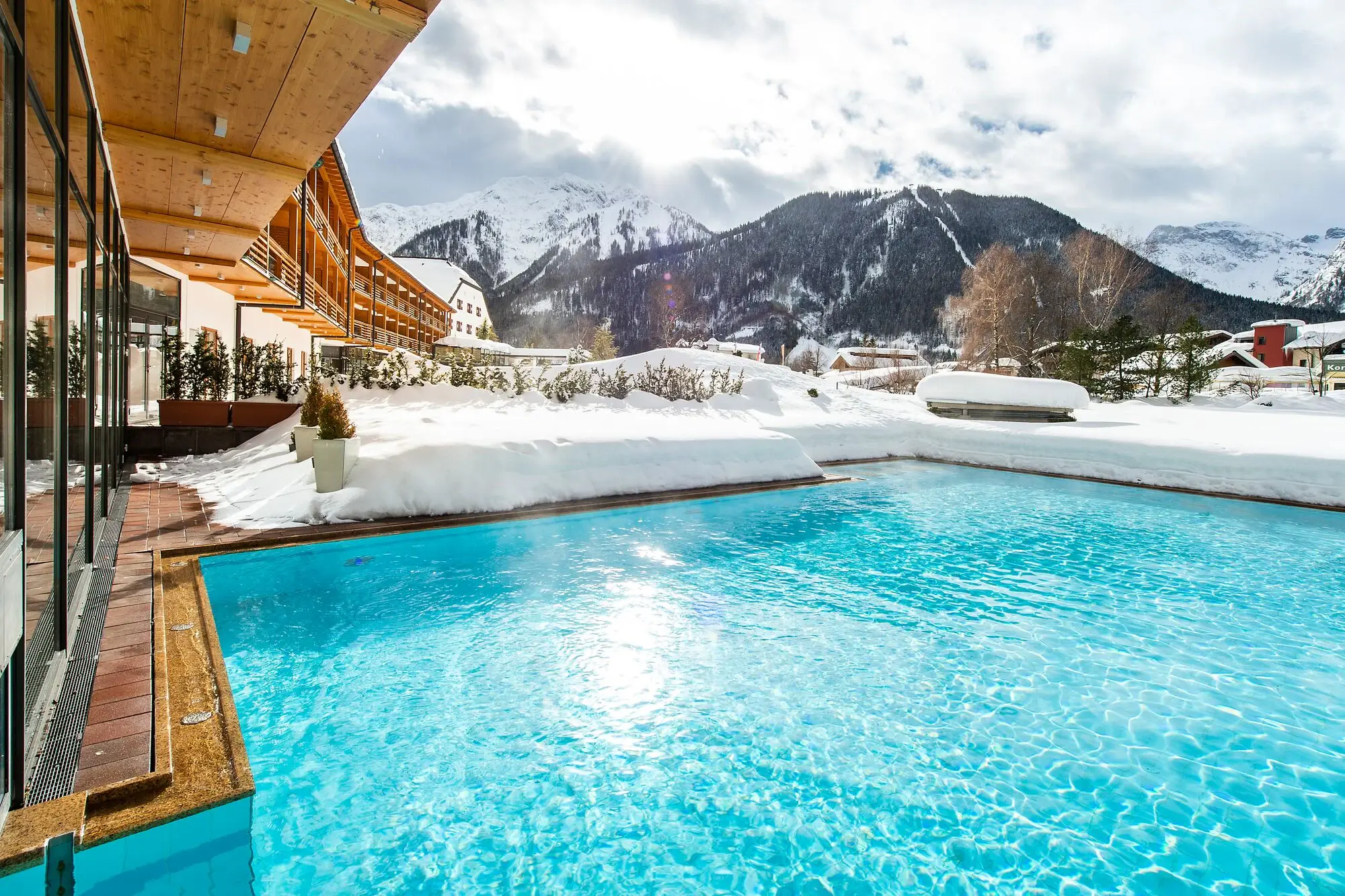 Schwimmbecken im Freien mit Schnee bedeckt, umgeben von Bergen.