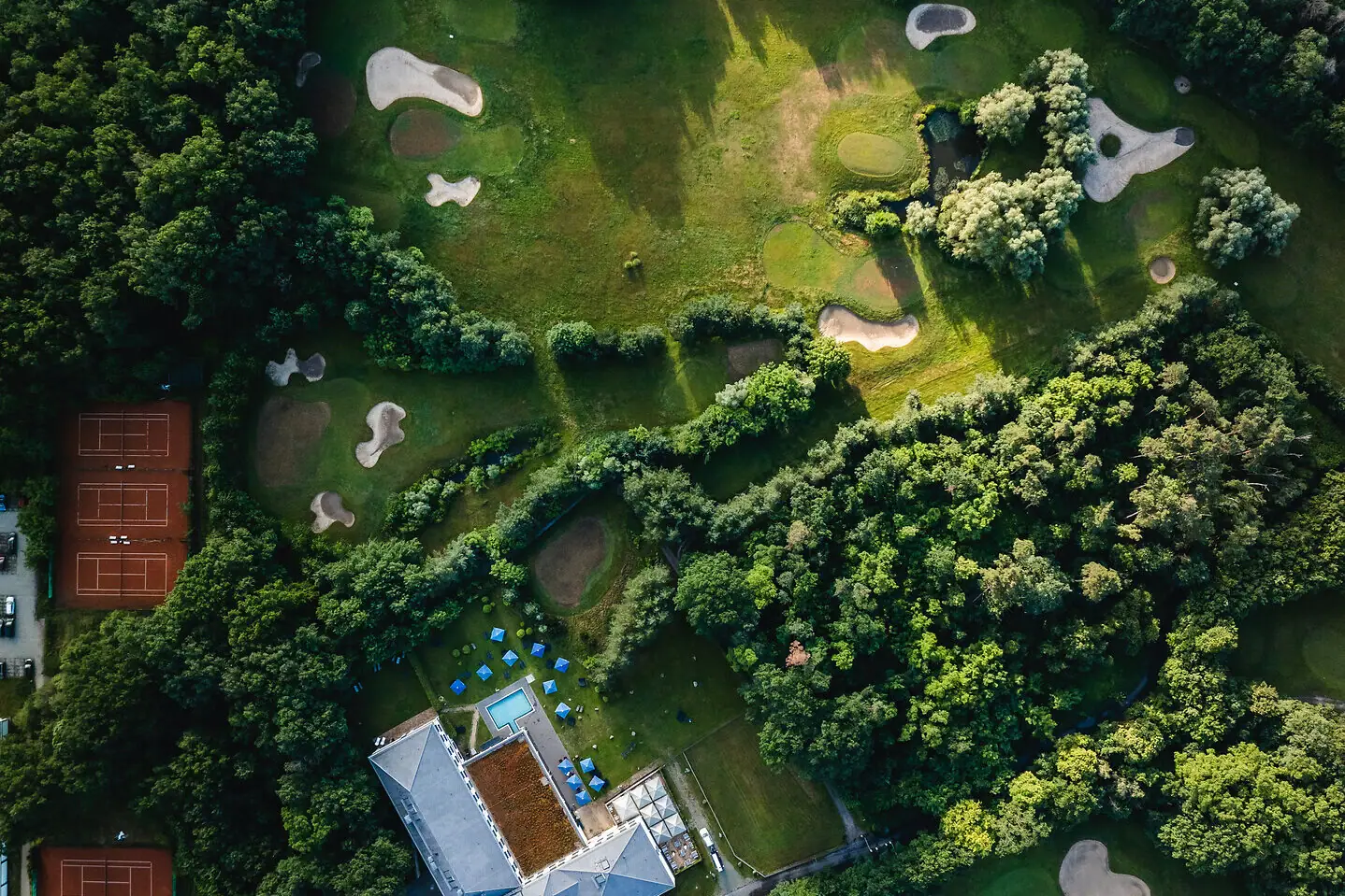 Golf in Bad Saarow Luftaufnahme eines Golfplatzes mit Bäumen und einem Wasserhindernis.