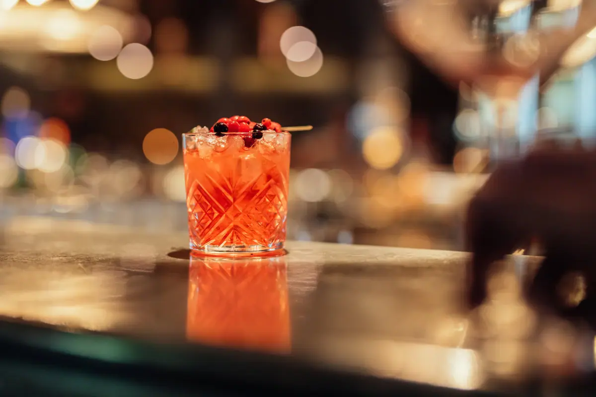 Drink Ein Glas mit einem Cocktail und Beeren als Garnitur.