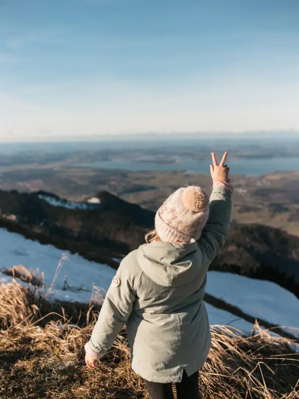 Eine Person steht auf einem Hügel und zeigt ein Peace-Zeichen.