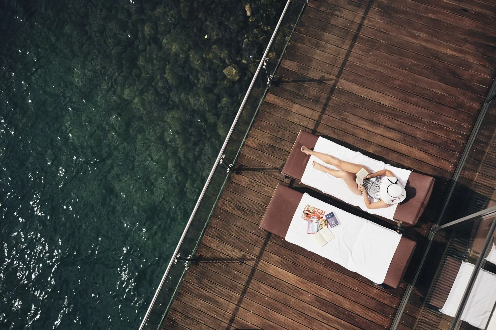 Liege am See Eine Frau liegt auf einem Liegestuhl neben Wasser.