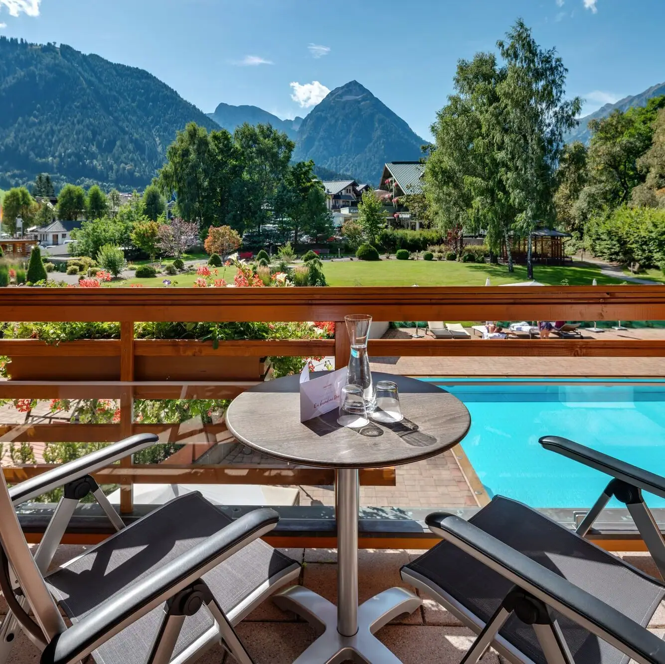 Ein Tisch und Stühle auf einem Balkon mit Blick auf einen Pool.