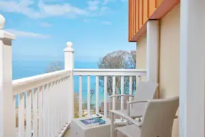 Ein weißer Stuhl und Tisch auf einem Balkon mit Blick auf das Meer.