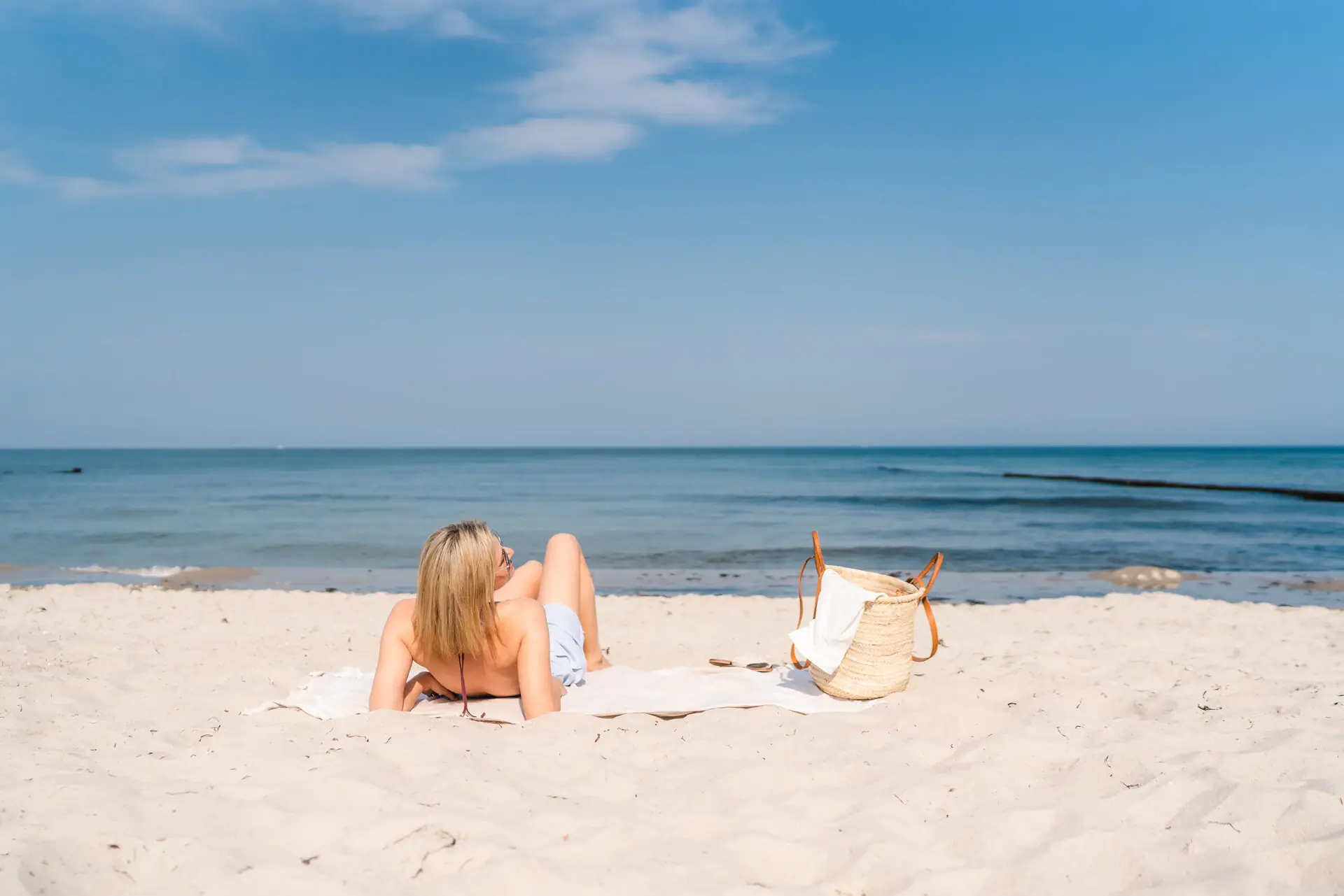 Eine Frau liegt auf einem Handtuch am Strand.