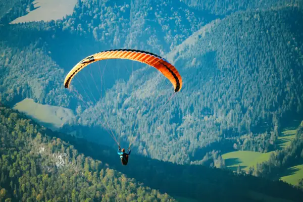 Eine Person beim Paragliding über einem Tal.