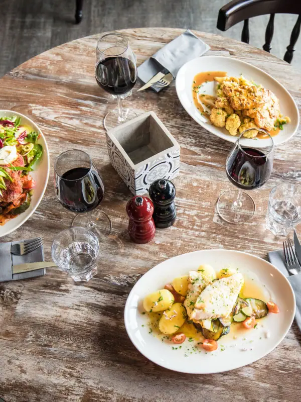 Abendessen im JEDERMANNS Ein Tisch mit Tellern voller Speisen und Weingläsern.