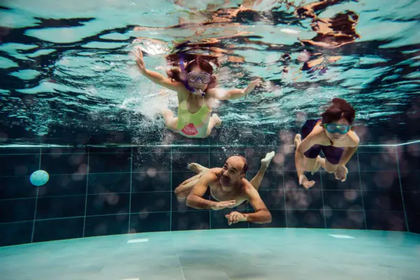 Eine Gruppe von Menschen schwimmt unter Wasser in einem Schwimmbad.