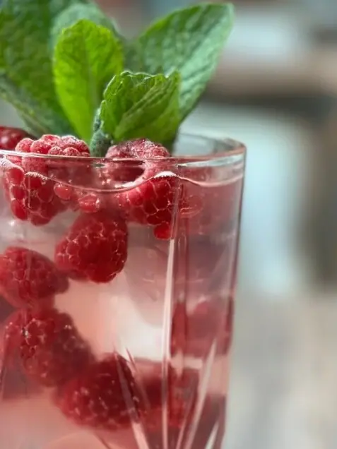 aja BSA Wosé Ein Glas mit Himbeeren und Blättern.