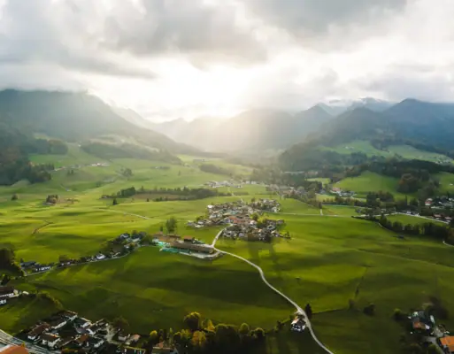 Urlaub in den Bergen Grüne Landschaft mit Bergen und Gebäuden im Vordergrund.