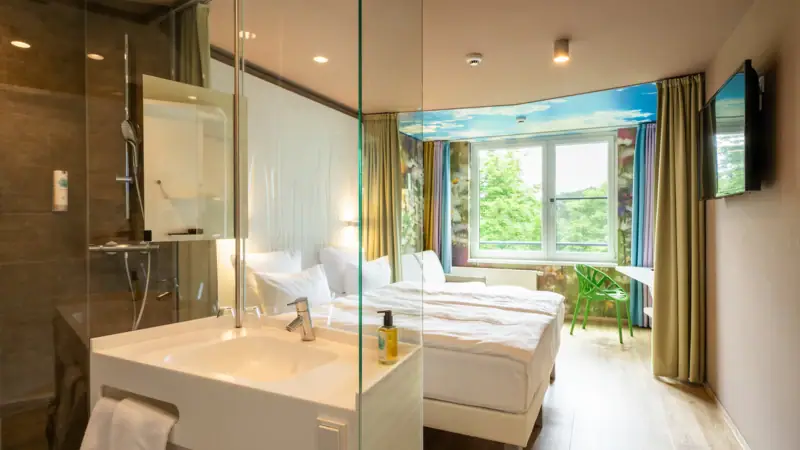 Ein Raum mit einer Glasdusche und zwei Betten.