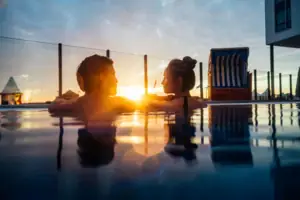 Außenpool Ein Mann und eine Frau im Außenpool bei Sonnenuntergang.