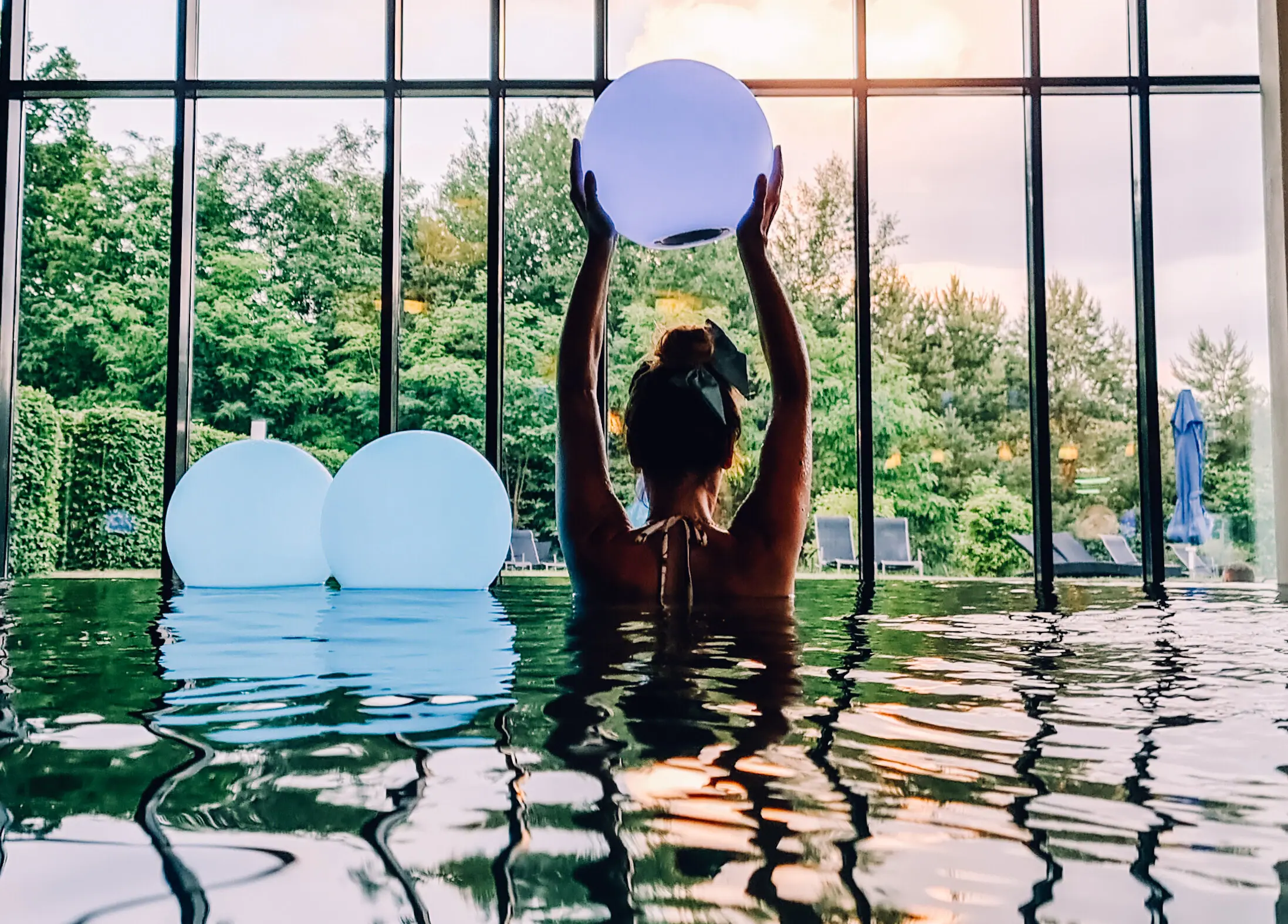 Innenpool aja Bad Saarow Eine Frau im Pool hält einen Ball.