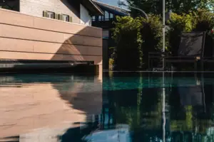 Pool mit Stühlen und Sonnenschirmen vor einem Berg.