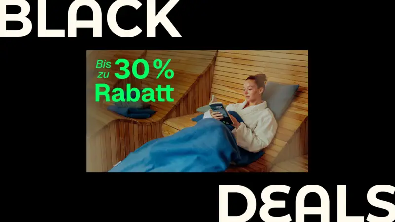 Eine Frau liegt auf einer Holzbank und liest ein Buch.