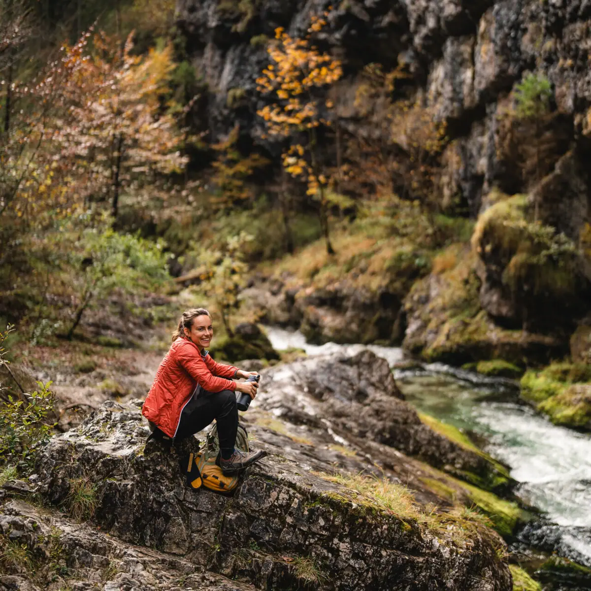 Eine Frau sitzt auf einem Felsen am Fluss.
