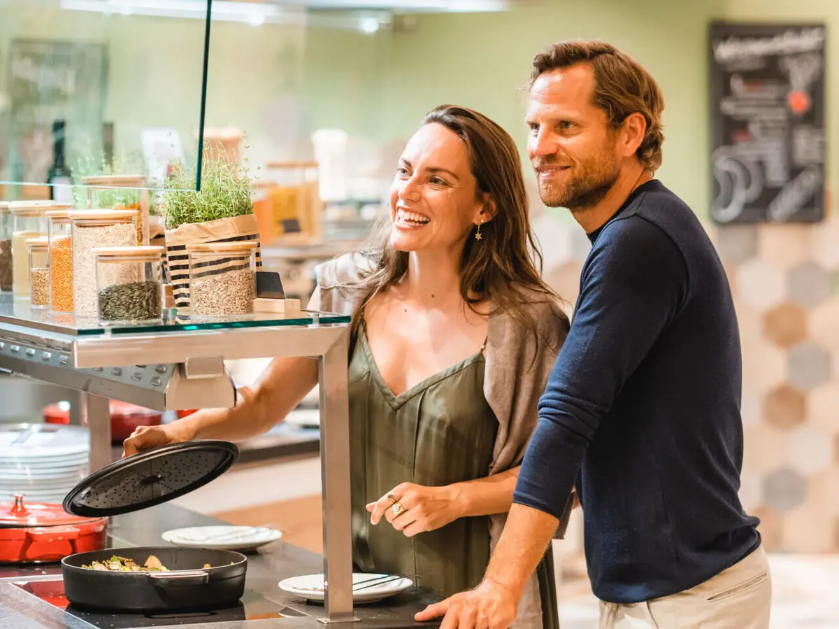 Ein Mann und eine Frau stehen neben einer Theke mit Essen.