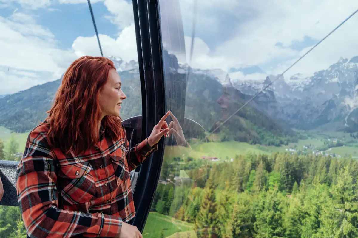 Eine Frau blickt aus dem Fenster einer Gondel auf Berge.