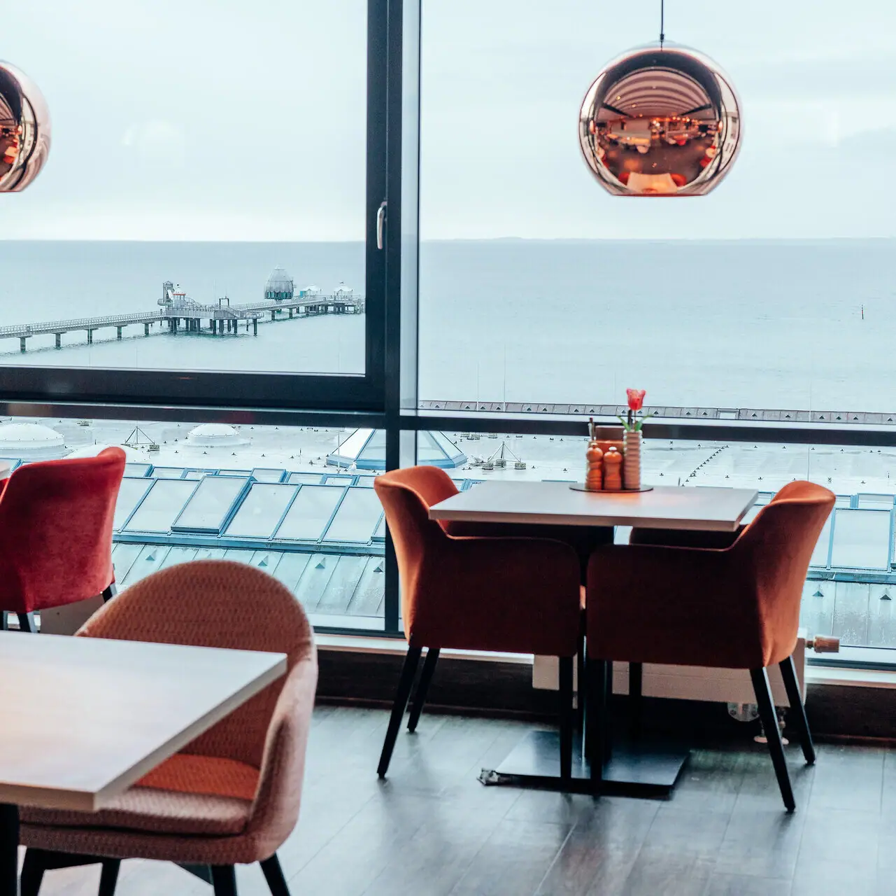 Ein Raum mit Blick auf den Ozean und einen Pier, mit einem Kaffeetisch im Vordergrund.