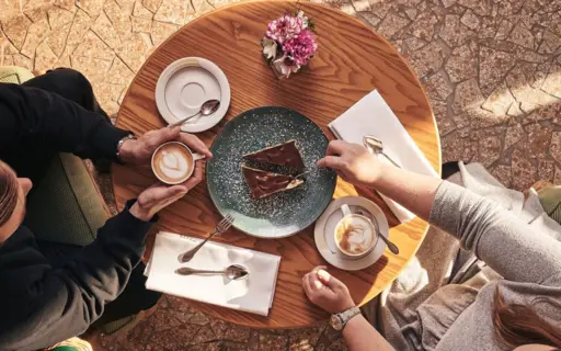 Eine Gruppe von Menschen sitzt an einem Tisch mit Kaffee und Kuchen.