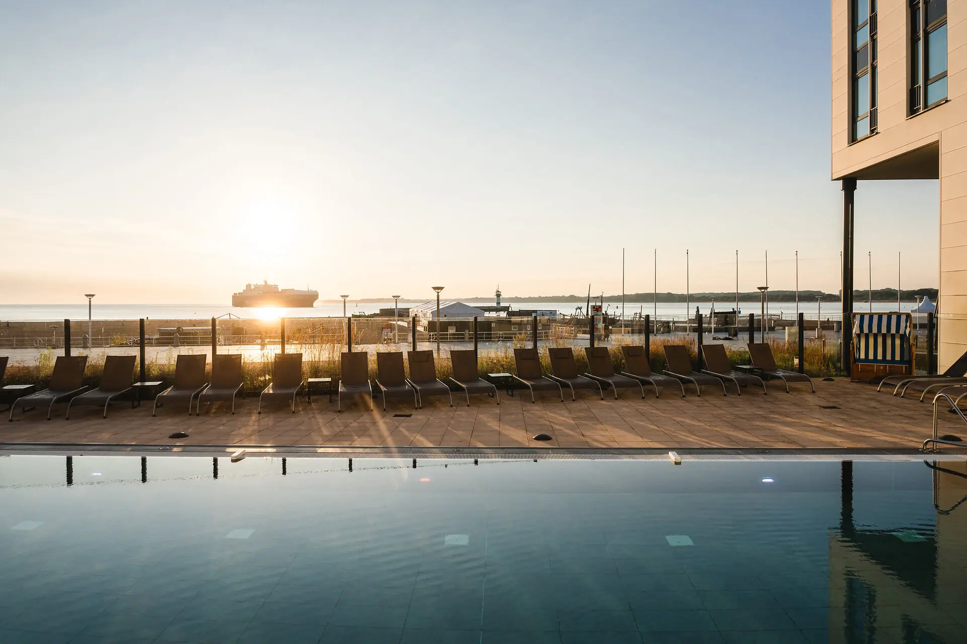 Pool mit Stühlen und einem Boot im Hintergrund.