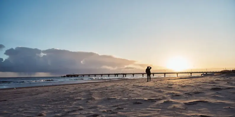 Eine ruhige Strandszene mit Wellen die aufs Ufer treffen in der Morgensonne. 