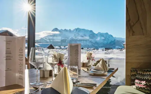 Ein Tisch mit Gläsern und Servietten, im Hintergrund ein Berg.